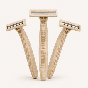 Trois rasoirs jetables biodégradables à deux lames avec longs manches texturés en paille de blé beige.